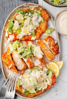 chicken parmesan pizza with lettuce and lemon wedges on a plate