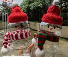 two snowmen in hats and scarfs inside glass jars