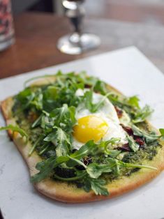 a pizza topped with greens and an egg sitting on top of a white paper towel