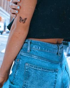 a woman with a butterfly tattoo on her left arm and right hand behind her back