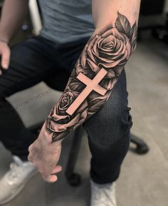 a man with a cross and roses tattoo on his arm