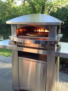 an outdoor pizza oven with two pizzas cooking on it's sides and the door open