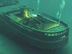 an old boat sitting in the water with algae growing on it's bottom half