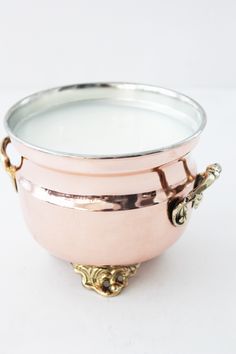 a large metal bowl with handles on the side and a candle in the middle, sitting on a white surface