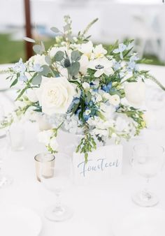 a centerpiece with white and blue flowers on a table