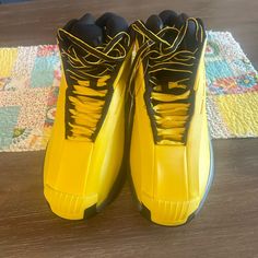 a pair of yellow and black sneakers sitting on top of a wooden floor