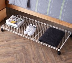 two pairs of shoes are sitting on a wire shelf next to a bed with pillows