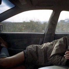 a man laying in the back seat of a car