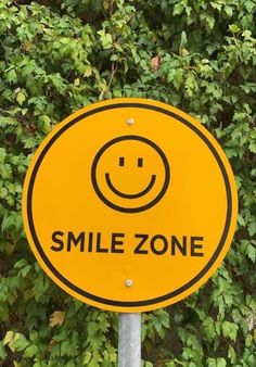 a smile zone sign sitting in front of some bushes