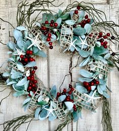 a wreath with red berries, green leaves and white starfishs on the front door