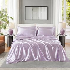 a bed covered in purple sheets and pillows