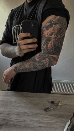 a man with tattoos on his arm holding a cell phone