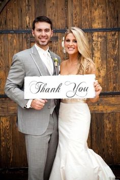 a bride and groom holding a sign that says thank you