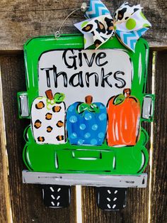 a green door with a sign that says give thanks and pumpkins painted on it