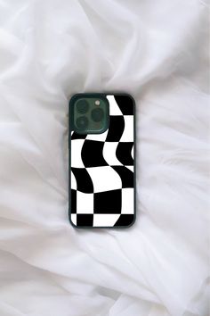 a black and white checkered iphone case laying on top of a bed covered in sheets