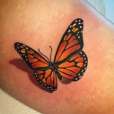 an orange and black butterfly tattoo on the back of a woman's left arm