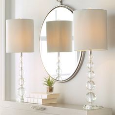 two lamps sitting on top of a white dresser next to a mirror and lamp shade