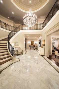 an elegant foyer with chandelier and marble flooring is seen in this image