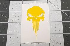 a yellow and white poster with a skull on it's face in the middle of a tiled floor