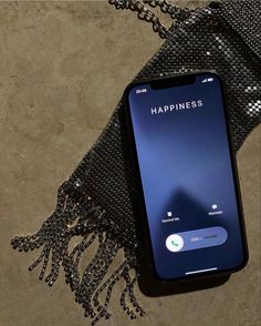 a cell phone sitting on top of a black bag with the word happiness written on it