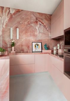 a kitchen with pink marble counter tops and cabinets, along with potted plants in vases