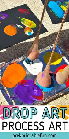 kids's hands painting with paint and wooden spoons on top of an art project