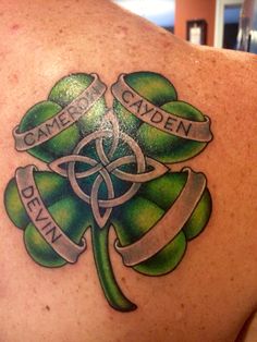 the back of a man's shoulder with a shamrock and name tattoo on it