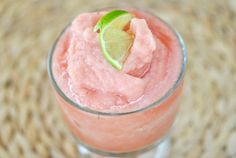 a close up of a drink in a glass with a lime slice on the rim