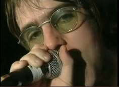 a close up of a person holding a microphone to their mouth and singing into it