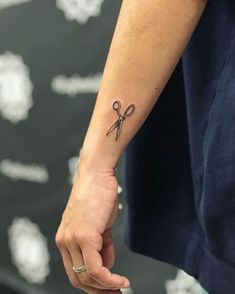 a person with a tattoo on their arm holding a pair of scissors in one hand