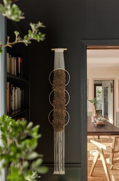 a room with a book shelf, table and chair next to a door that has a plant hanging from it