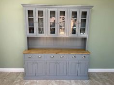 a gray china cabinet with glass doors and drawers on the top, in a room with tile flooring