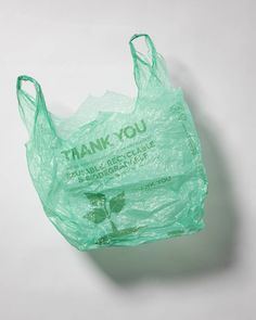 a green plastic bag with the words thank you written on it, sitting on a white surface