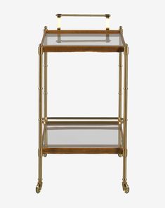 an antique brass and glass bar cart with two shelves on wheels, the top shelf is empty