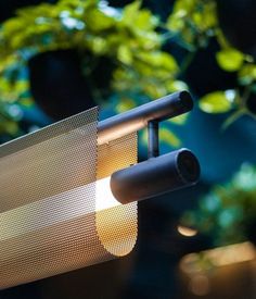 a close up of a lamp on a table with plants in the backround