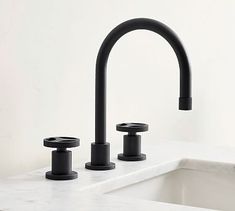 two black faucets sitting on top of a white counter