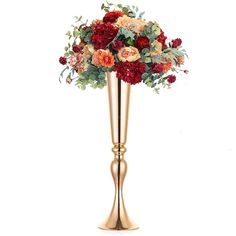 a gold vase filled with red and orange flowers