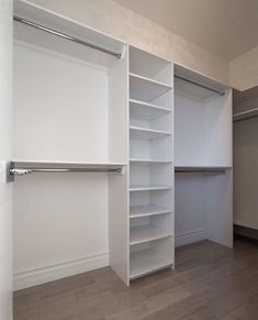 an empty walk in closet with white shelving and wood flooring on the walls