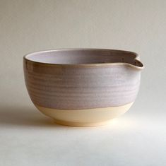 a gray and white bowl sitting on top of a table next to a wall in the background