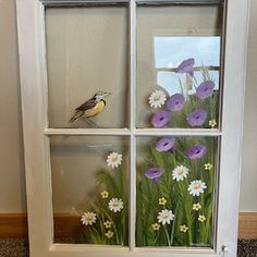 a window with flowers painted on it and a bird sitting in the window sill