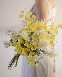 a woman holding a bouquet of yellow and white flowers