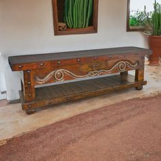 an old wooden bench sitting in front of a potted plant and mirror on the wall