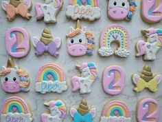 decorated cookies with unicorns, rainbows and numbers on a marble countertop in the shape of letters