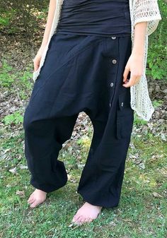 black bloomers out of heavy cotton fabric ॐ with two baggy bags and one regular pocket on the right leg. on the left leg is a raw of wooden buttons. it has an elastical waist band so it fits on perfect to your body. with the elastic bands on the ankles you can wear it as a short or 3/4 pants visually, this harem pants fits wonderfully with everything that is psychedelic, whether it's hippie, goa or psytrance parties, but also for yoga or meditation as well as in everyday life - with these comfor Hippie Style Black Wide Leg Pants, Black Wide Leg Hippie Pants, Black Baggy Bohemian Bottoms, Baggy Cotton Yoga Pants For Festival, Black Cotton Yoga Pants For Summer, Festival Cotton Harem Pants With Drop Crotch, Baggy Black Cotton Harem Pants, Bohemian Black Festival Bottoms, Bohemian Black Yoga Pants For Festivals