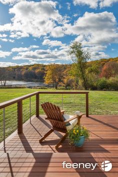 a wooden chair sitting on top of a wooden deck next to a lush green field