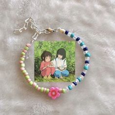 two people sitting on the ground next to each other with beads and charms around them