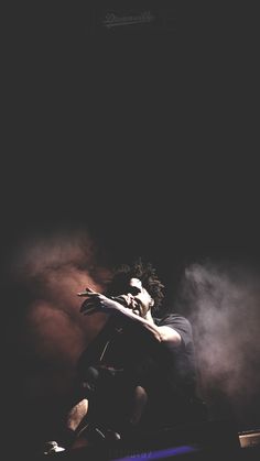 a man sitting on top of a stage with his arms out in front of him