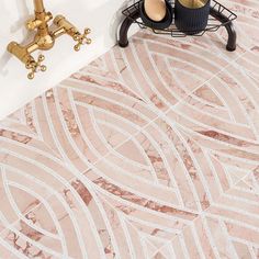 a bathroom with pink marble flooring and gold faucets on the wall next to it