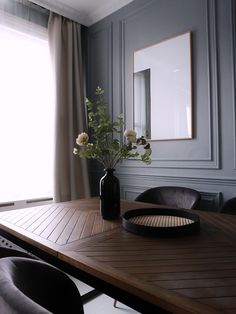 a vase with flowers sitting on top of a wooden table in front of a window