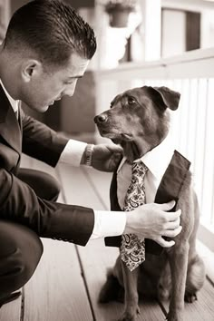 a man in a suit is petting a dog wearing a tie on the porch